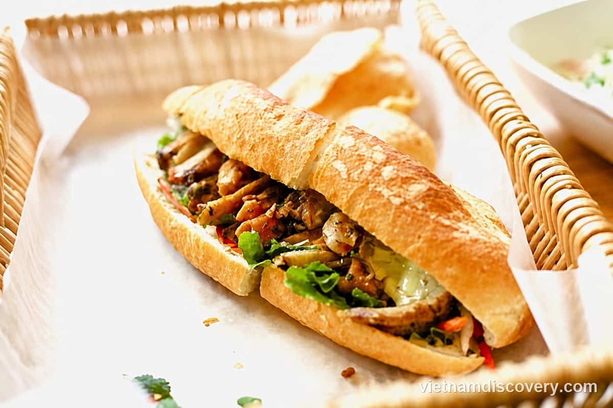 A bánh mì filled with sliced meat and lettuce in a basket