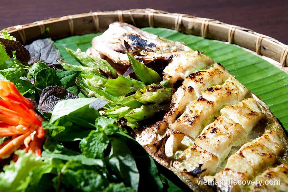 Skinned and scored cá bò, grilled, with herbs