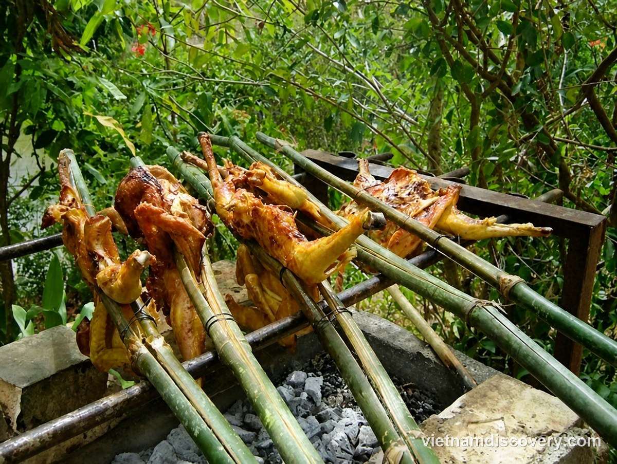 Whole chickens grilling on bamboo spits over charcoal