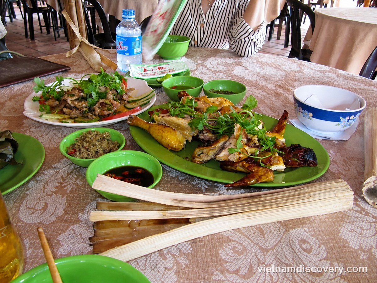 A table with grilled chicken, dipping bowls and opened lam rice tubes