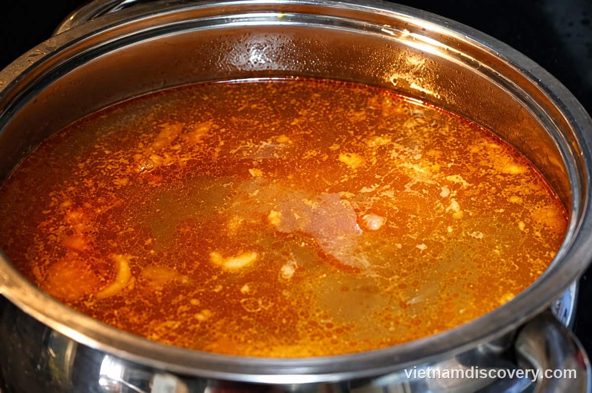 Straining the broth and frying garlic in annatto oil