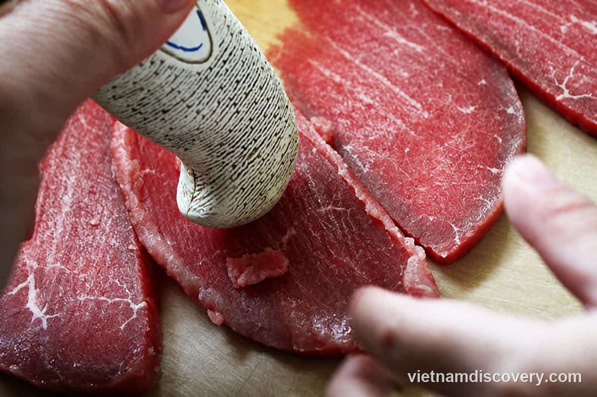 Pounding the beef slices to tenderise them