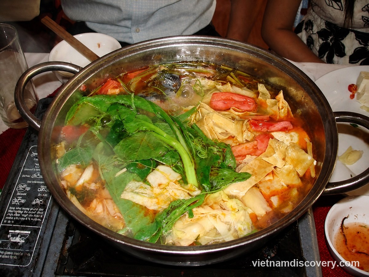 Goat hotpot with greens and cabbage on a table burner