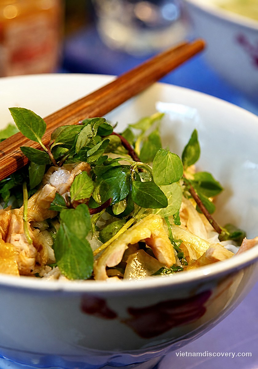 Phở trộn topped with herbs, with chopsticks in the bowl