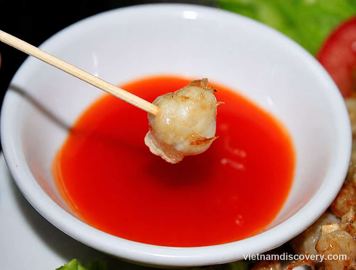 A squid tooth on a skewer, dipped in chilli sauce