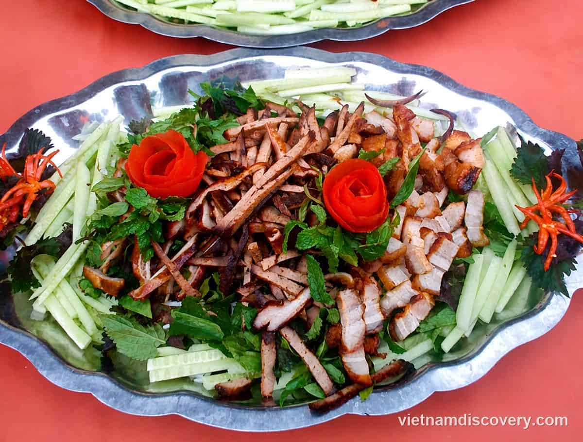 A platter of sliced roast meats with herbs, cucumber and tomato roses